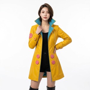 May include: A bright yellow leather coat featuring a contrasting teal inner lining and collar. The coat includes four circular pink accents on the front and one on the right sleeve, paired with a black top and black shorts underneath the jacket.
