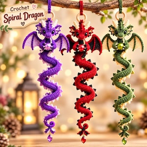 May include: Three hanging crochet spiral dragon ornaments in purple, red, and green. Each dragon features wings, horns, a spherical bead held in its claws, and a dangling crystal at the tail. A sign at the top left reads Crochet Spiral Dragon.