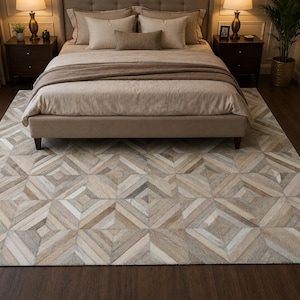 May include: A rectangular area rug featuring a geometric pattern composed of stitched leather tiles in varying shades of beige, cream, grey, and brown. The rug displays a repeating diamond and square motif across its entire surface area.