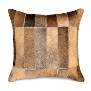 May include: A square throw pillow constructed from rectangular patches of genuine cowhide leather. The surface features a patchwork design with varying shades of brown, tan, and dark chocolate, showcasing the natural texture of the animal hair.