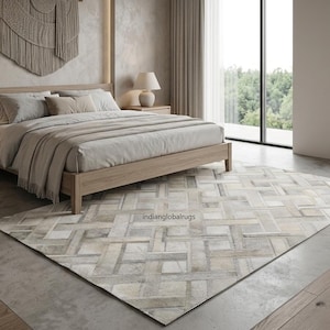 Könnte beinhalten: Ein rechteckiger Teppich mit einem geometrischen Webmuster in Beige-, Creme- und Grautönen. Der Teppich zeigt ein strukturiertes, ineinandergreifendes Design mit sichtbaren Nähten und einer kurzflorigen Oberfläche auf einem hellen Boden.