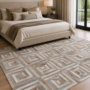 May include: A rectangular area rug featuring a repeating geometric pattern of concentric squares in shades of beige, tan, brown, and cream. The rug is constructed from stitched panels with varying textures and tones, creating a layered visual effect.
