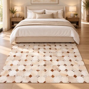 Puede incluir: Una alfombra rectangular con un patrón geométrico de baldosas octogonales y cuadradas en tonos crema, beige y marrón. La alfombra está compuesta por piezas de piel cosidas entre sí, creando una superficie texturizada en el suelo.