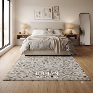 May include: A rectangular area rug featuring a mosaic pattern of small, square tiles in varying shades of gray, beige, and white. The rug is positioned on a light wood floor and displays the text INDIAN GLOBAL RUGS in white lettering.