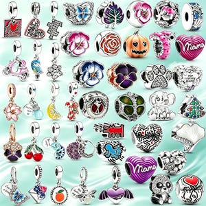 Puede incluir: Una colección de dijes de metal en tono plateado con diversos diseños que incluyen flores, corazones, animales, frutas y temas festivos. Muchos dijes están decorados con esmalte de colores, piedras transparentes brillantes y detalles grabados.