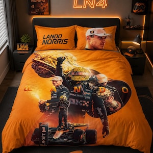 Könnte beinhalten: Ein orangefarbenes Bettwäsche-Set mit einem großen Grafikdruck von Lando Norris in Rennkleidung, einem Formel-1-Auto und Trophäen. Die Kissenbezüge zeigen den Text Lando Norris und ein Porträt des Fahrers. Das Design enthält die Buchstaben L, A, N, D, O.
