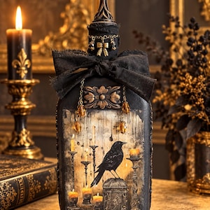 May include: A decorative glass bottle painted black with a central illustration of a black crow perched on a pedestal surrounded by lit candles. The bottle features a black fabric bow, gold-toned chain accents with beads, and a pointed black topper.