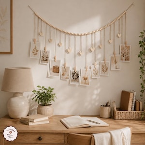 May include: A wall-mounted photo display featuring a long string of light-colored wooden beads draped in a curve. Multiple vertical jute strings hang from the beads, each holding a small rectangular photograph with a wooden clip and a wooden heart.