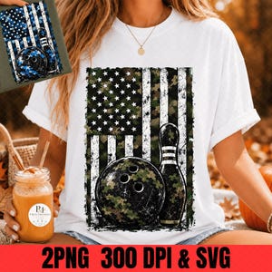 May include: A white t-shirt featuring a graphic of an American flag with a camouflage pattern. The design includes a black bowling ball and a bowling pin overlaid on the flag. The same graphic is visible on a separate piece of fabric in the corner.