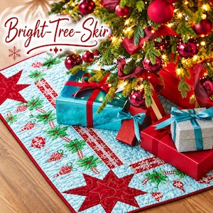 Könnte beinhalten: Ein gesteppter Weihnachtsbaumteppich mit hellblauem Hintergrund und einem wiederkehrenden Muster aus roten Ornamenten und grünen Weihnachtssternen. Der Stoff ist mit großen roten Sternen und einem roten Rand verziert. Der Text Bright-Tree-Skir ist sichtbar.