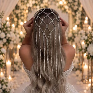 Può includere: Un copricapo color argento caratterizzato da una corona a reticolo realizzata con singoli strass. L'accessorio include molteplici lunghe catene di strass pendenti che ricadono dalla parte posteriore della testa a cascata.