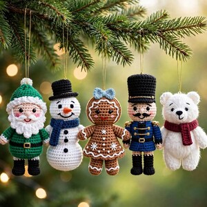 Pode incluir: Um conjunto de cinco enfeites de Natal em crochê pendurados numa árvore, incluindo um Pai Natal em verde, um boneco de neve com cachecol azul, uma figura de gengibre com laço azul, um quebra-nozes em uniforme azul e um urso polar branco.