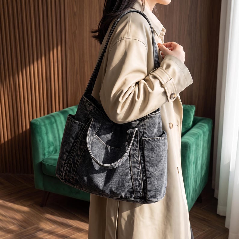 May include: A dark gray acid-wash denim tote bag featuring a spacious main compartment, two sturdy shoulder straps, and two external side pockets. The bag is constructed from a textured fabric with visible stitching details along the seams and edges.