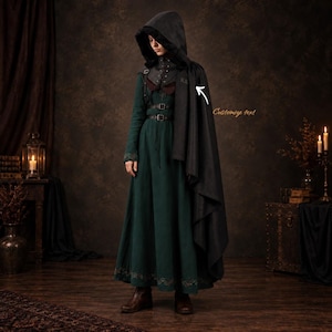 May include: A dark green floor-length dress with a black hooded cloak. The cloak features a white arrow pointing to the text "Customize text" on the shoulder. The dress has a fitted bodice with two black buckled straps across the chest and waist.