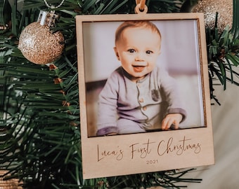 Puede incluir: Un adorno navideño de madera con una foto de un bebé. El adorno está decorado con el texto "Luca's First Christmas 2021".