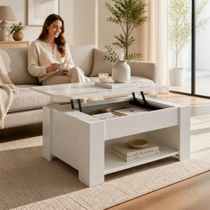 Peut inclure: Une table basse rectangulaire blanche dotée d'un mécanisme de plateau relevable révélant un compartiment de rangement intérieur. La table présente une étagère inférieure ouverte contenant deux livres empilés, dont l'un est intitulé Live Beautiful.