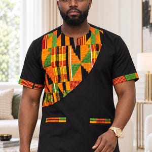 May include: A black short-sleeved shirt and matching cap featuring a vibrant, multi-colored Kente-inspired geometric pattern in orange, yellow, green, and red. The shirt has a round neckline, two front pockets, and a diagonal panel design.