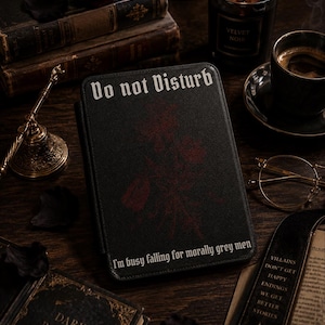 Może przedstawiać: Czarne etui na czytnik e-booków z białym napisem "Do not Disturb" u góry i "I'm busy falling for morally grey men" u dołu, z ciemnoczerwoną ilustracją kwiatową wyśrodkowaną na przedniej okładce.