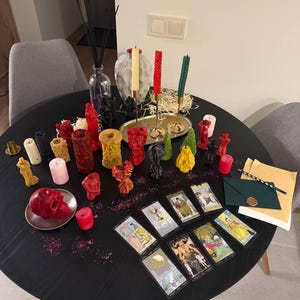 a table with various candles, tarot cards, and other decorative items arranged on it.