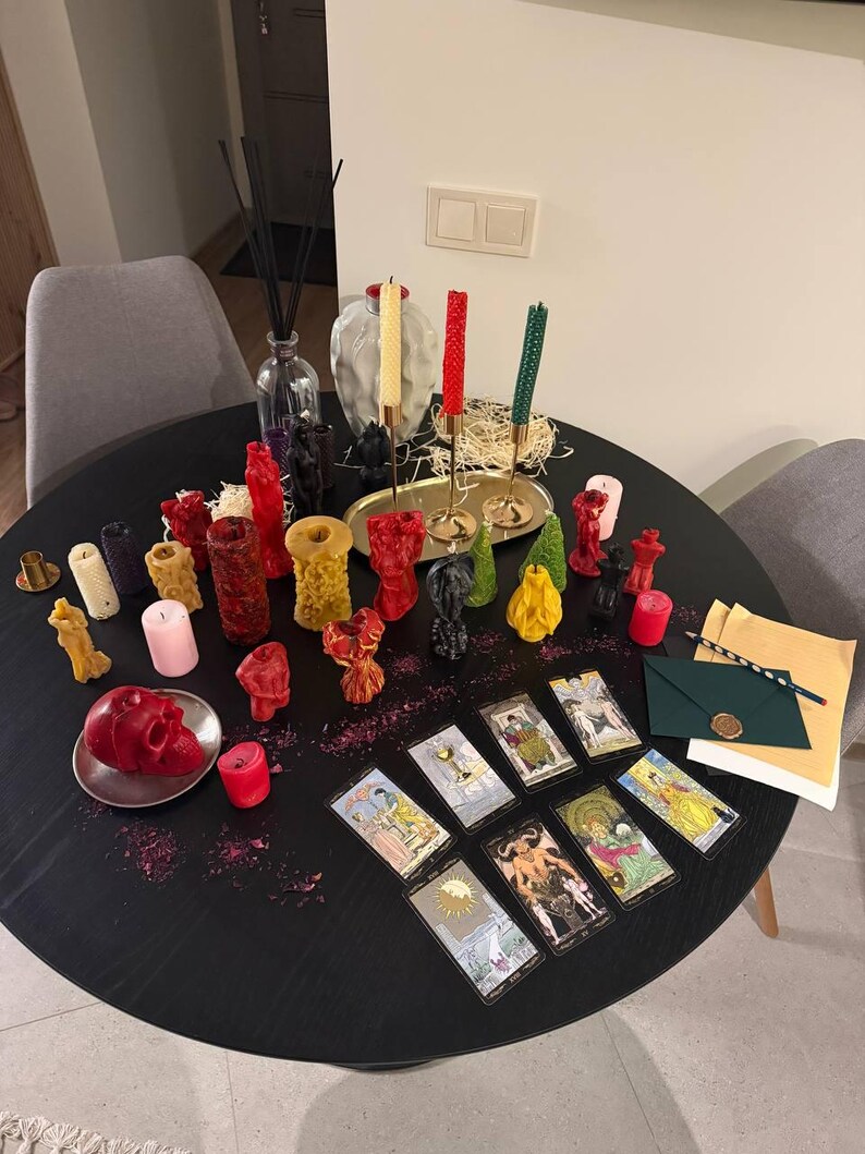a table with various candles, tarot cards, and other decorative items arranged on it.