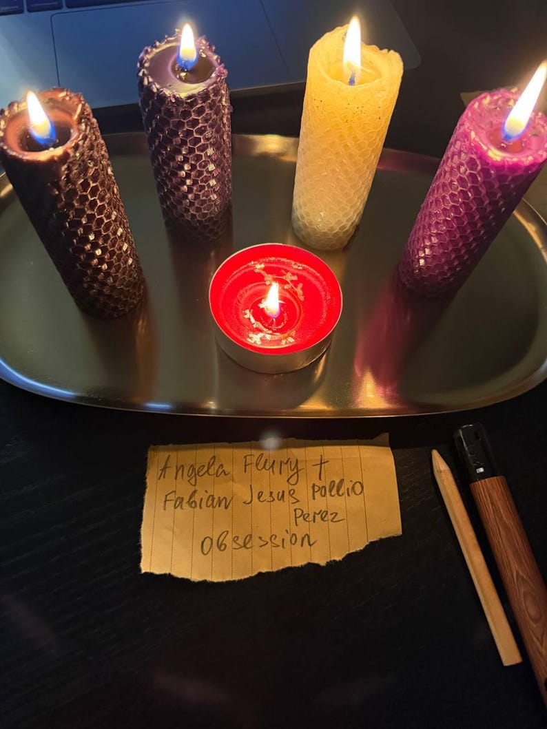 a tray with four candles of different colors - purple, yellow, and red - along with a red candle and a handwritten note.