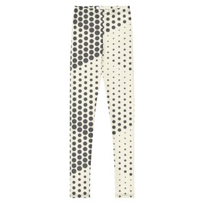 May include: Full-length leggings featuring a cream-colored base with a dark gray halftone dot pattern. The design consists of varying sizes of circular dots arranged in a gradient effect, creating a dense cluster on one side and sparse spacing.