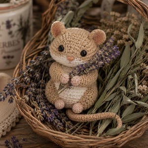 May include: A small, crocheted mouse toy made with light tan and cream yarn. The mouse has round ears, black bead eyes, and a small pink nose. It is holding a bundle of dried lavender sprigs in its front paws and has a long, thin crocheted tail.