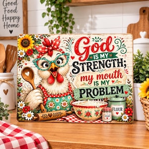May include: A rectangular decorative sign featuring a cartoon chicken wearing a red polka dot headscarf and teal glasses. The chicken holds a wooden spoon. The text reads: God IS MY STRENGTH; my mouth IS MY PROBLEM. Includes a bowl and jars.