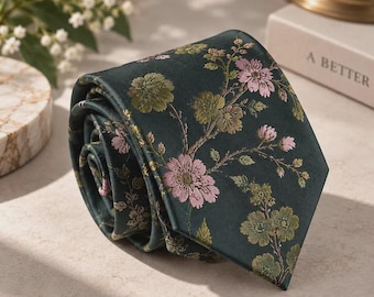 May include: A dark green necktie featuring a woven floral pattern with light pink and muted olive green blossoms and leaves. The fabric has a smooth, satin-like finish with a pointed tip, showcasing a detailed botanical design across the surface.