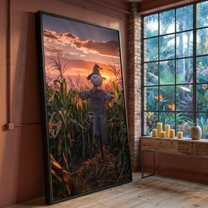 Peut inclure: Une œuvre d'art murale rectangulaire encadrée représentant un épouvantail dans un champ de maïs au coucher du soleil. L'épouvantail porte un chapeau pointu et des vêtements gris. Le ciel orange et violet domine les tiges de maïs.