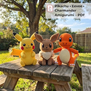 May include: Three crocheted amigurumi figures: a yellow Pikachu with red cheeks, a brown Eevee with a cream-colored chest, and an orange Charmander with a cream-colored belly. The text reads: Pikachu • Eevee • Charmander Amigurumi – PDF.