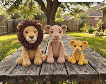 Puede incluir: Tres figuras de leones tejidas a ganchillo que incluyen un león grande con melena marrón oscura, una leona mediana de color beige claro y un cachorro de león pequeño de color amarillo dorado. Cada figura tiene detalles faciales bordados.