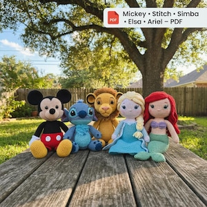 May include: Five crocheted dolls representing Mickey, Stitch, Simba, Elsa, and Ariel. A white rectangular label at the top displays the text: Mickey • Stitch • Simba • Elsa • Ariel – PDF. The dolls are arranged in a row on a wooden surface.