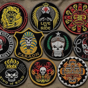May include: A collection of ten embroidered patches featuring various designs including a lion, skulls with wings, a pharaoh, a sun motif, and text such as LIVE TO RIDE, FARAON, FREE LIFE, and KING OF ROAD, rendered in black, red, yellow, and white.