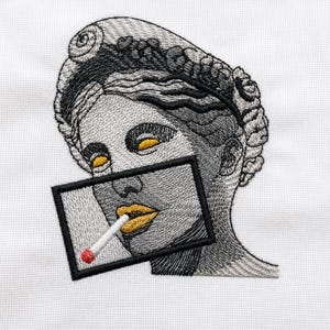 Puede incluir: Un parche bordado sobre tela blanca que muestra un busto clásico en escala de grises con un peinado en espiral. Un marco rectangular negro se superpone a la parte inferior del rostro, resaltando labios amarillos sosteniendo un cigarrillo.