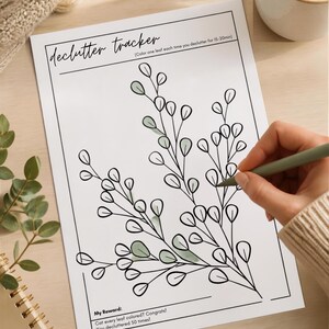 May include: A white paper declutter tracker with black ink outlines of branches and leaves. The text reads: declutter tracker, Color one leaf each time you declutter for 15-20min, My Reward: Got every leaf colored? Congrats! You decluttered 50 times!