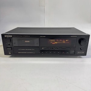 Puede incluir: Una pletina de casete estéreo Pioneer CT-5801R negra con compartimento de carga frontal, pantalla digital con la palabra TAPE, varios botones de control, toma de auriculares y un gran mando giratorio para el nivel de grabación.