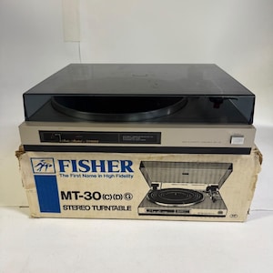 May include: A Fisher MT-30 stereo turntable with a dark grey dust cover, resting on its original cardboard box. The box features the Fisher logo, the text "The First Name in High Fidelity," and "MT-30 (C)(D)G STEREO TURNTABLE" with an illustration.