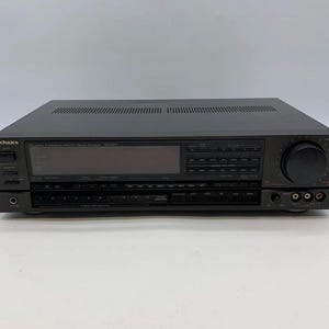 Puede incluir: Un receptor estéreo AM/FM Technics Quartz Synthesizer SA-427P de color negro con una gran pantalla digital central, un botón de volumen prominente a la derecha, múltiples botones de control, una toma de auriculares y puertos de entrada de audio.