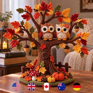 Può includere: Un albero autunnale all'uncinetto con due gufi appollaiati su un ramo. L'albero è decorato con foglie rosse, arancioni, gialle e verdi e ghiande pendenti. Alla base ci sono un fungo rosso, due zucche e una piccola staccionata.