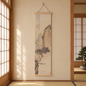 Peut inclure: Une tenture murale verticale en forme de rouleau présentant une peinture à l'encre traditionnelle d'un paysage montagneux avec un arbre, un petit bateau sur l'eau et une calligraphie. Le rouleau est monté sur des tiges en bois clair.
