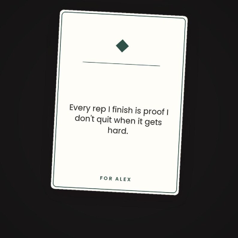 May include: A rectangular white card with a thin dark border featuring a dark green diamond icon above a horizontal line. The text reads: Every rep I finish is proof I don't quit when it gets hard. The bottom of the card includes the text: FOR ALEX.