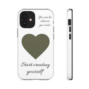 Könnte beinhalten: Eine weiße Smartphone-Hülle mit einem dunkelolivgrünen Herz in der Mitte. Der Text "You can be whoever you want" ist über dem Herz aufgedruckt, und "Start creating yourself" steht darunter in einer schwarzen, eleganten Serifenschrift.