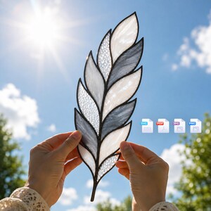 May include: A stained glass feather ornament featuring alternating segments of translucent white, textured clear, and marbled gray glass held together by dark metal solder lines. The design includes four file format icons labeled SVG, PDF, JPG, and PNG.