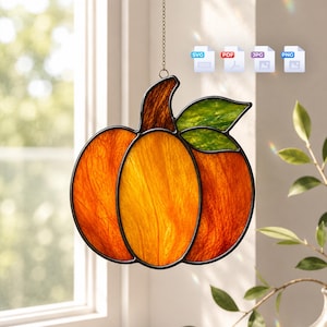 May include: A stained glass pumpkin suncatcher featuring orange and yellow textured glass panels with a brown stem and green leaves, framed in black metal, suspended by a thin chain, accompanied by SVG, PDF, JPG, and PNG file icons.