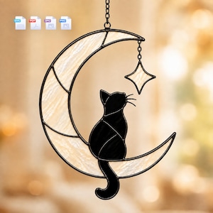 May include: A stained glass suncatcher featuring a crescent moon made of cream-colored textured glass and a black glass cat sitting on the moon. A small four-pointed star hangs from the upper curve of the moon by a short metal chain.