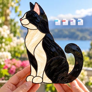 May include: A stained glass cat suncatcher featuring a black and cream-colored pattern with pink inner ears. The design is composed of distinct glass segments joined by dark metal lines. Four file format icons labeled SVG, PDF, JPG, and PNG are visible.