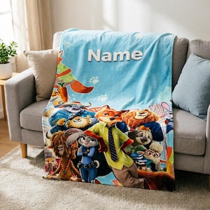 May include: A light blue fleece blanket featuring a colourful graphic print of various animated animal characters from Zootopia, including a fox and a rabbit. The word Name is printed in white capital letters at the top centre of the blanket.