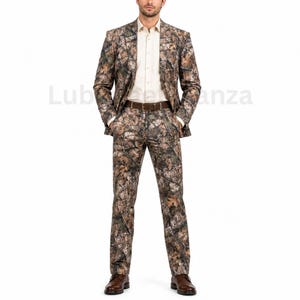 Peut inclure: Un costume deux pièces composé d'une veste et d'un pantalon à motif camouflage forestier dans des tons marron, beige et vert. L'ensemble est porté sur une chemise boutonnée beige clair unie avec une ceinture et des chaussures en cuir marron.
