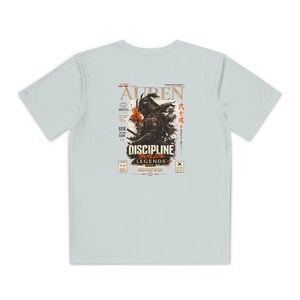 Peut inclure: Un t-shirt à manches courtes gris clair avec un motif au dos. Le design représente un samouraï en armure avec des touches orange, entouré de texte incluant AUREN, DISCIPLINE BUILDS LEGENDS et des caractères japonais dans un style magazine.